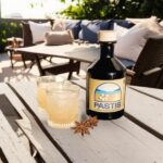 kit fabrication de pastis DIY dans une boîte de la taille d'une brique, contenant des sachets d'épices et d'aromates, une bouteille vide, et une notice explicative pour la préparation de pastis fait maison